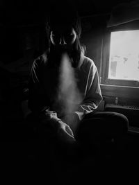 Man smoking while sitting against window