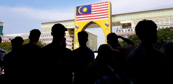 Rear view of silhouette people standing against buildings