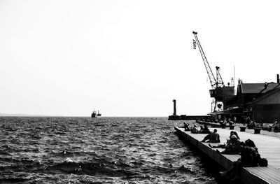 Sailboat on pier by sea against clear sky