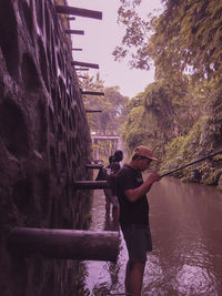 Rear view of men standing by canal against sky