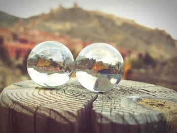 Close-up of crystal ball on landscape against sky