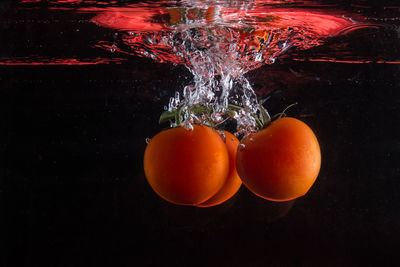 Close-up of orange in water against black background