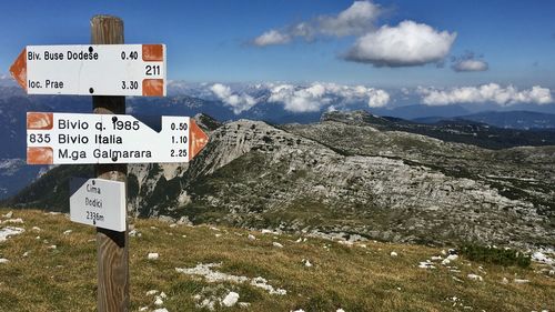 Road sign by mountains against sky