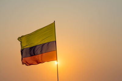 Low angle view of flag against orange sky