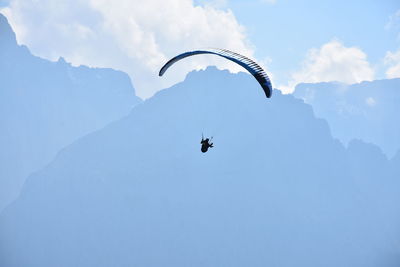Low angle view of person paragliding against mountains