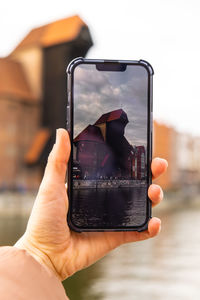 Traveler taking photo of ancient crane - zuraw old town in gdansk. the riverside on granary island