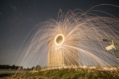 Light trails on field against sky at night