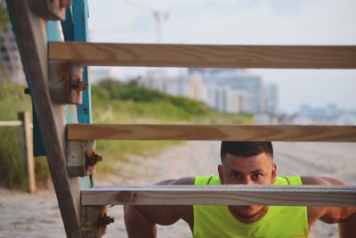 Portrait of young man exercising by wooden staircase