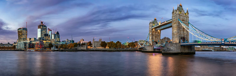 Tower bridge over river against sky at dusk