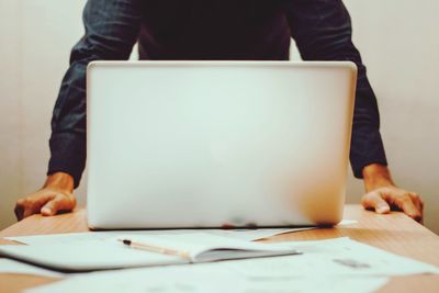 Midsection of man using mobile phone while sitting on table