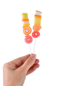 Close-up of hand holding multi colored candies against white background