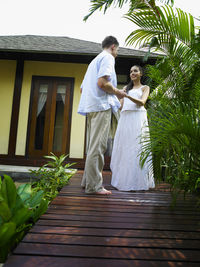 Full length of couple standing on boardwalk against house