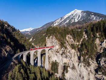 Scenic view passenger train crossing landwasser viaduct in front of mountains