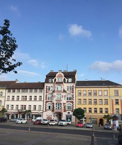 Cars on road by buildings in city against sky