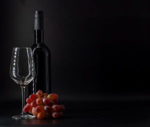 Fruits in glass on table against black background