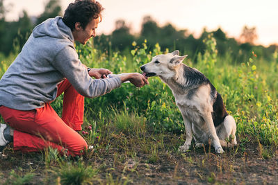 Side view of man with dog on field