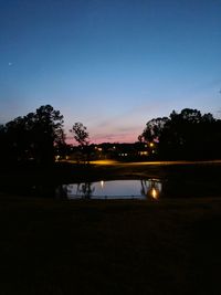 Silhouette trees by lake against sky at sunset