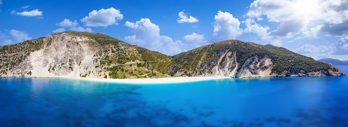 Panoramic view of sea by mountain against sky