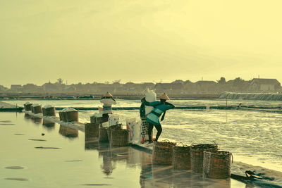 Rear view of people working at salt lake during sunset