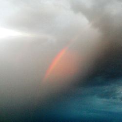 Low angle view of rainbow over cloudy sky