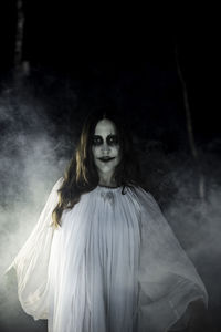 Portrait of female ghost in amidst smoke in dark