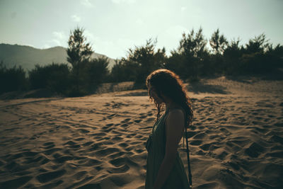 Side view of woman standing on beach against sky