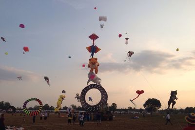 Low angle view of balloons flying against sky during sunset