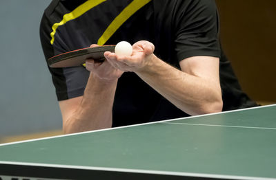 Midsection of man serving while playing table tennis