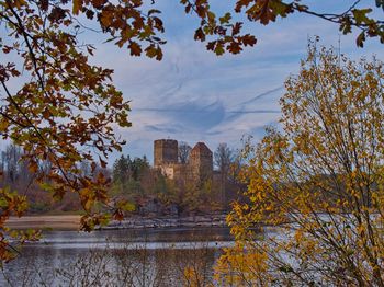 Trees by lake against sky during autumn