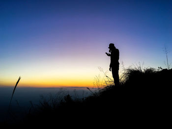 Silhouette man photographing at sunset