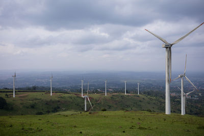 Windmills on field against sky