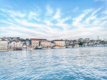 Sea by cityscape against sky