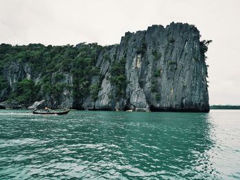 Scenic view of rocks by sea against sky