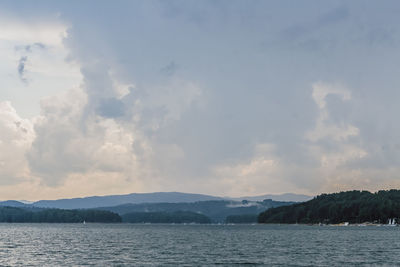 Scenic view of sea and mountains against cloudy sky