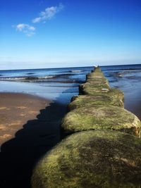 Scenic view of rocks on beach against blue sky