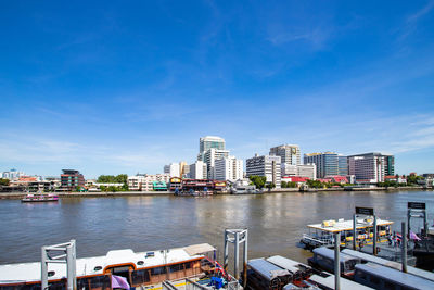 Boats in river against buildings in city