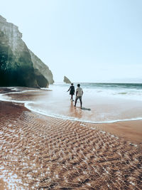 People on beach against clear sky