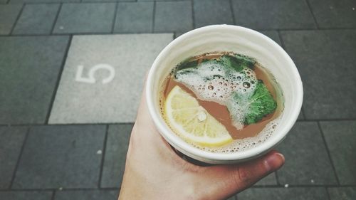 Cropped image of woman holding ginger tea against footpath