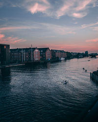 View of river and buildings against sky during sunset