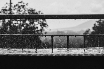 Close-up of wet railing against sky during rainy season