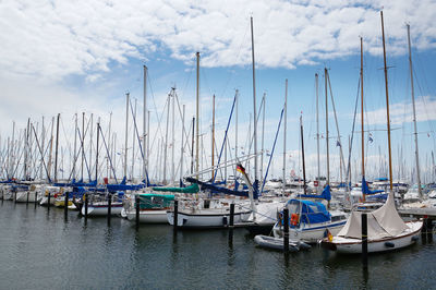 Boats moored at harbor against sky