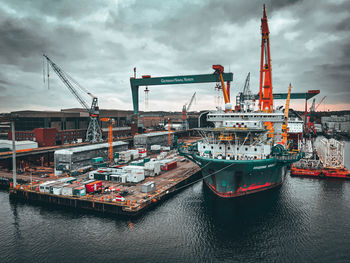 Cranes at commercial dock against sky