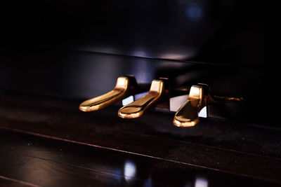 Close up of golden piano pedals under sunlight through the window. with detail wooden texture.