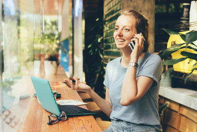 Young girl manager talking on the phone in a cozy coworking