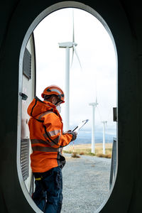 Inspector technician at the door of a wind turbine seen from inside