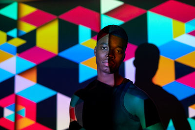 Portrait of young man standing against multi colored wall