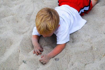 High angle view of boy playing with sand at beach