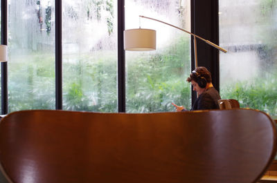 Woman sitting on chair in glass window