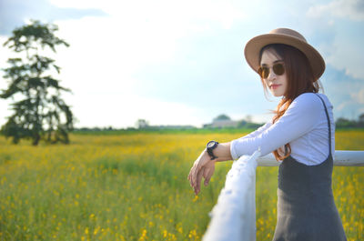 Young woman wearing sunglasses while standing on field