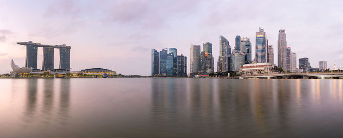 Sea by modern buildings against sky in city